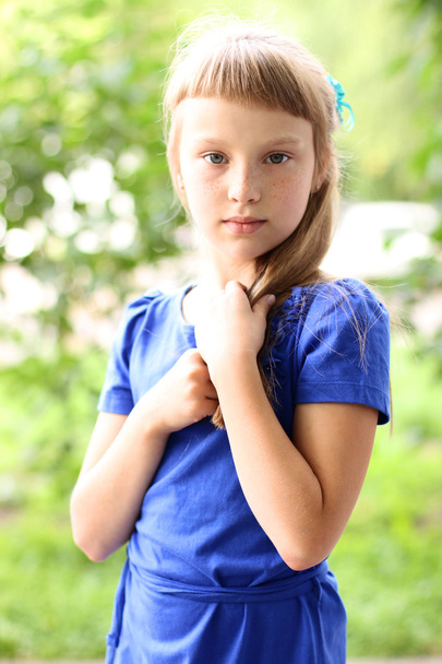 Weinig meisje blauwe jurk heldere zonnige zomer dag park onder groene struiken, op zoek idee concept van teen fashion stijl, vormt voor portret - Foto, afbeelding