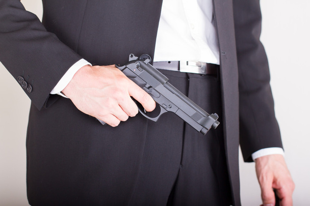 άνθρωπος με όπλο, επαγγελματικό κοστούμι, εστίαση του όπλου - Φωτογραφία, εικόνα