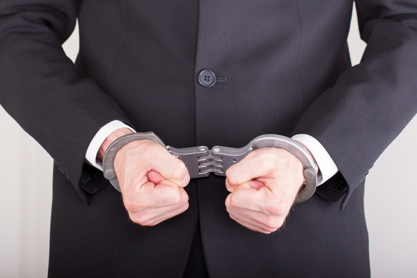 Man with handcuffs, business suit, focus on the handcuffs - Photo, image
