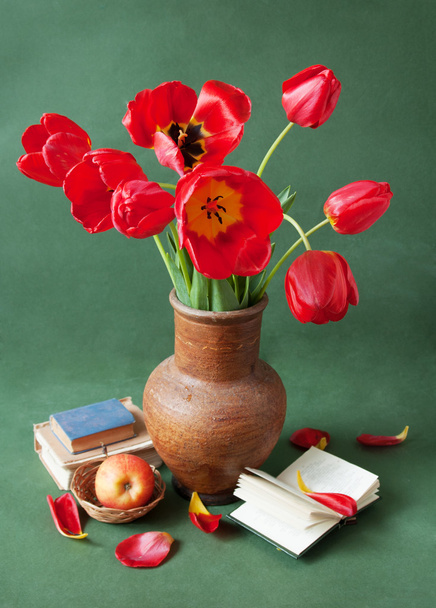 красные цветы мака в вазе с яблоками и книгами на зеленом фоне - Фото, изображение