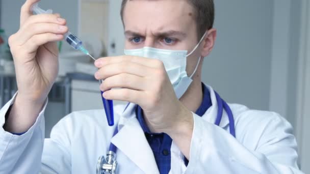 Portrait de jeune médecin caucasien homme versant un liquide bleu d'une seringue à un tube
, - Séquence, vidéo