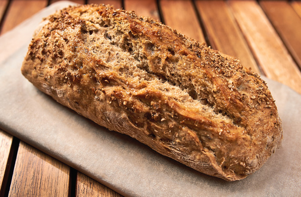 Loaf of homemade bread on wooden background, food closeup. - Photo, image