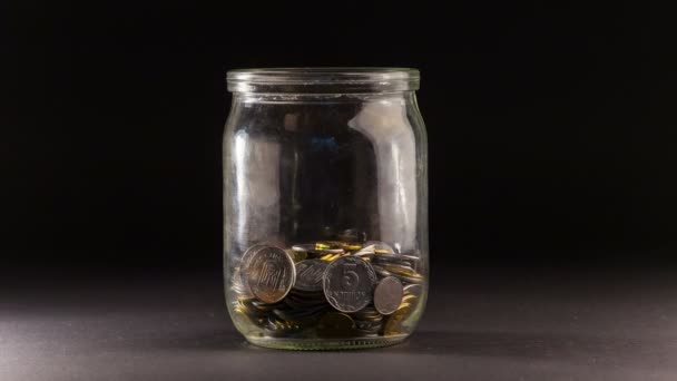 Zeitraffer fallender Münzen im Glas auf schwarzem Hintergrund. 4k ultra hd - Filmmaterial, Video