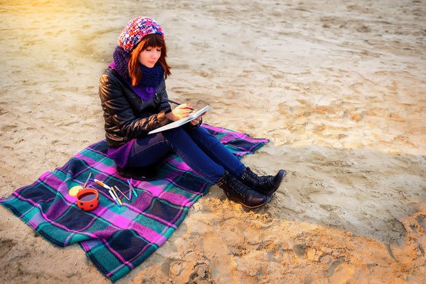 güzel kız sahilde oturan ve bir not kayıtları vardır - Fotoğraf, Görsel