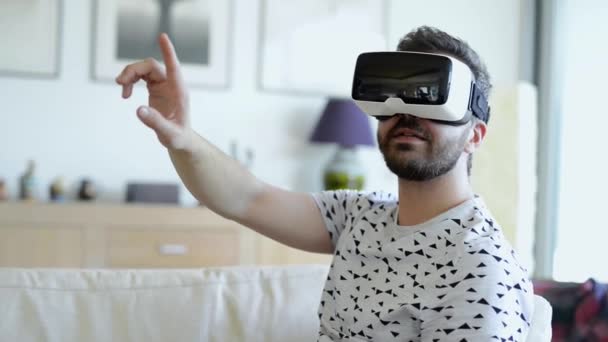 Man wearing virtual reality goggles. Studio shot, white couch - Кадри, відео