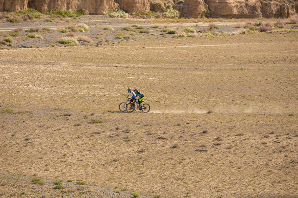 Young man on a mountain bike riding and relaxing in Charyn canyon, Kazakhstan - 写真・画像