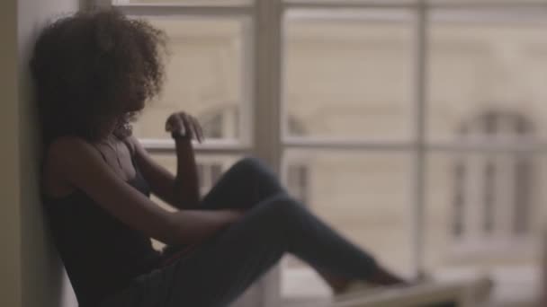 Mooie Afrikaanse vrouwen zittend op de windowsil en zorgvuldig kijkt uit op het raam - Video