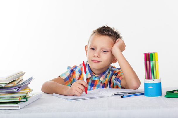 Κουρασμένος σχολείο αγόρι με το θλιμμένο πρόσωπο κάνει μαθήματα - Φωτογραφία, εικόνα