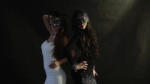 Δύο κορίτσια στη μάσκες που θέτουν σε μαύρο φόντο - Πλάνα, βίντεο