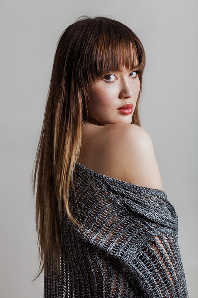 Beautiful girl portrait wearing grey sweater and looking back - Photo, Image