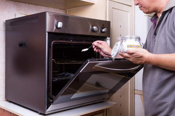 Persoon beregening baking soda in vette oven als reinigingsmiddel - Foto, afbeelding