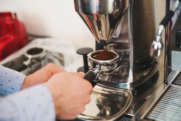 Quelqu'un détient une partie de la machine à café avec des grains de café moudre
 - Photo, image