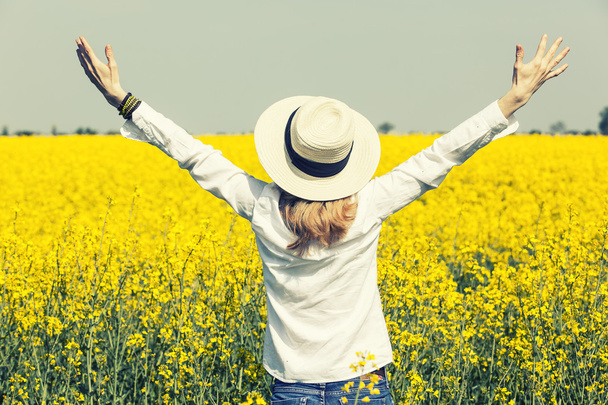 happy beautiful girl in front of  rapeseed field in bloom with open hands greeting sunny spring day ,freedom and prosperity concept - Photo, Image