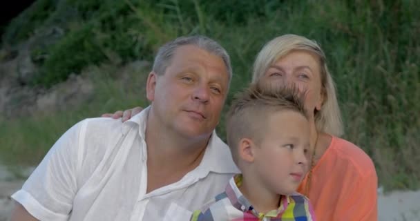 Nieto cosquillas abuelos cuello mientras está sentado en la playa
 - Imágenes, Vídeo