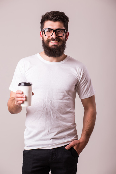 Barbudo joven con café en la mano mira a la cámara
  - Foto, Imagen