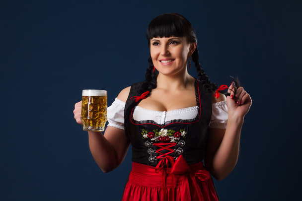 Mooie brunette vrouw in Beierse gekleed met glas bier - Foto, afbeelding