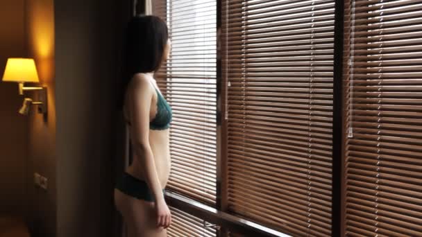 Beautiful woman in sexy lingerie in front of the window - Imágenes, Vídeo