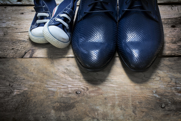 father's shoes and kids sneakers side by side on rustic wood  - Foto, Bild