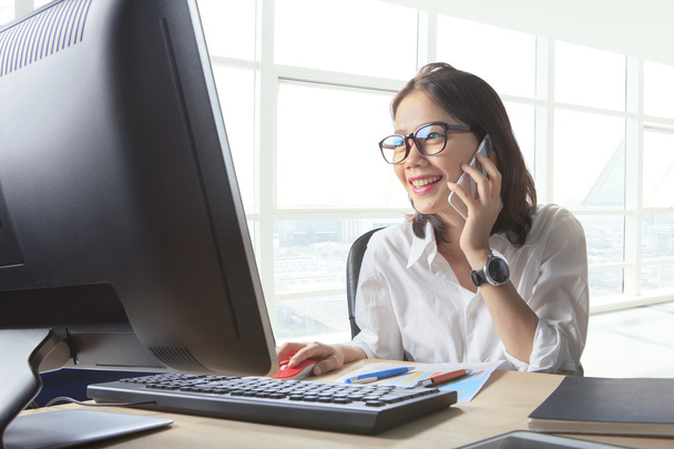young working woman talking to phone with watching on computer o - Photo, Image