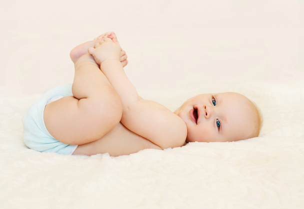 Feliz bebé sonriente acostado jugando en la cama en casa
 - Foto, Imagen