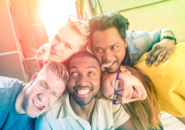 Beste vrienden nemen selfie buitenshuis met terug verlichting - Happy vriendschap concept met jongeren plezier samen - vrede en liefde tegen racisme - veelkleurige filter en zonneschijn halo flare - Foto, afbeelding