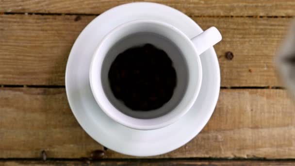 Verter granos de café en una taza en una mesa de madera vieja, vista superior
 - Metraje, vídeo