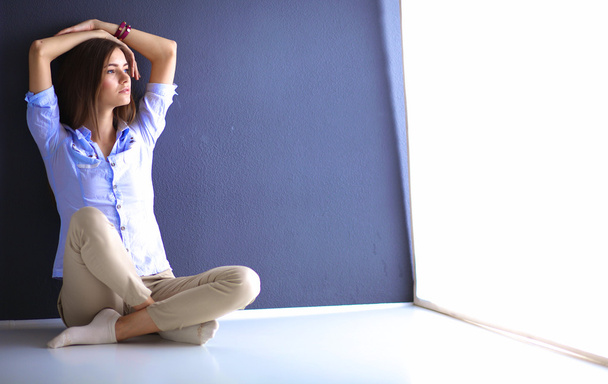 Young woman sitting on the floor near dark wall - Фото, зображення