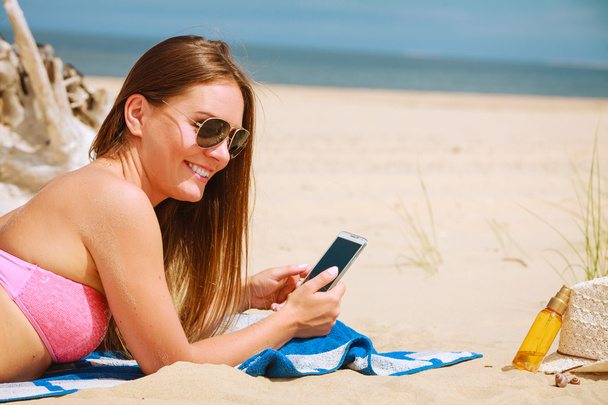 Woman on beach texting on smartphone. - Zdjęcie, obraz