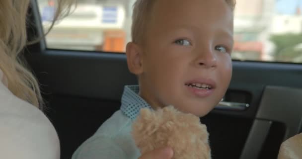 Chlapec s plyšovou hračkou na zadním sedadle auta - Záběry, video