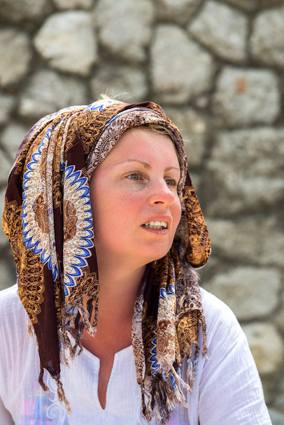 πορτρέτο μιας γυναίκας με ένα μαντήλι σε ένα κεφάλι με φόντο ένα πέτρινο τοίχο - Φωτογραφία, εικόνα