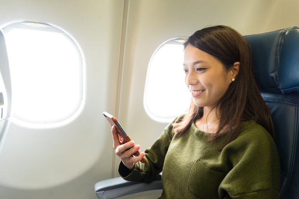 Жінка в літаку за допомогою мобільного телефону
 - Фото, зображення