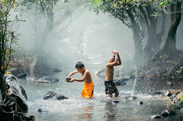 Kaksi poikaa leikkii vedellä.
 - Valokuva, kuva