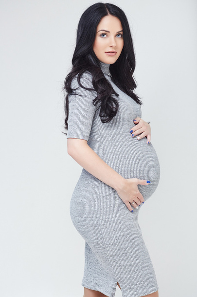 Těhotná bruneta žena v šedých šatech - Fotografie, Obrázek