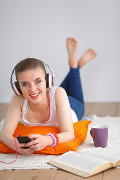 Young woman lying on floor and listen to music - Foto, Bild