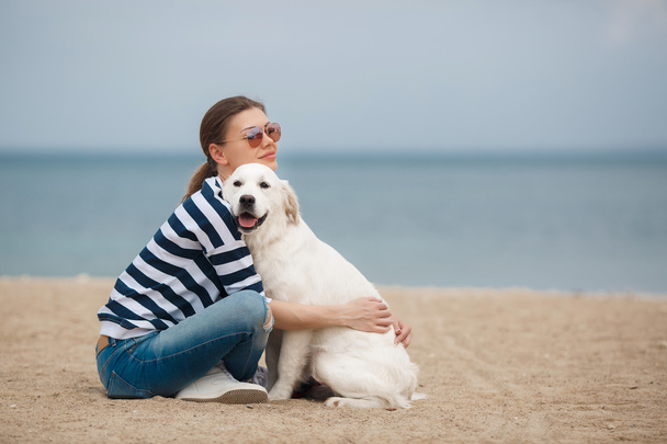 Jeune femme avec un chien sur une plage déserte
 - Photo, image