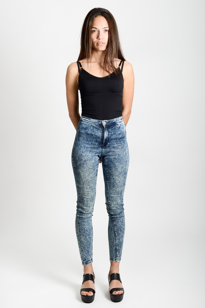 Молода жінка в чорному баку зверху і блакитних джинсах
 - Фото, зображення