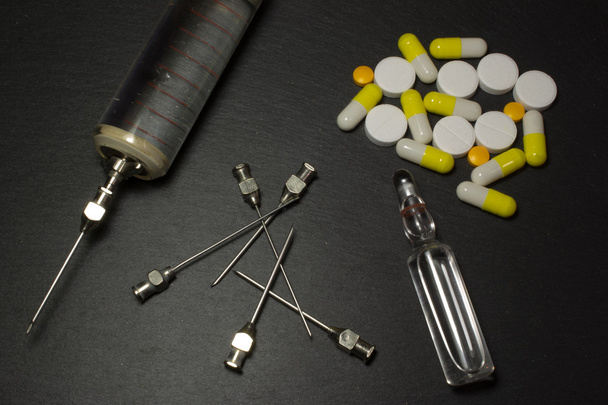 Siringa medica e pillole su sfondo scuro
 - Foto, immagini