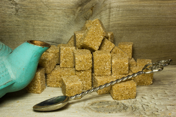Cubi di zucchero di canna marrone e cucchiaio su sfondo di legno
 - Foto, immagini