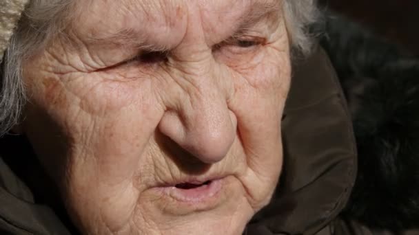 Portret van oude sprekende vrouw. Serieuze oma zitten buiten en spreken. Close-up - Video