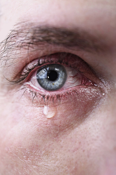 悲しいとうつ病の苦痛の涙で泣いている男の青い目のクローズ アップ - 写真・画像