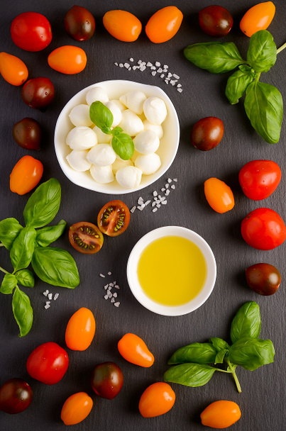 Włoskie jedzenie składników mozzarella, pomidory, bazylii i oliwy z oliwek na czarnym tle - Zdjęcie, obraz