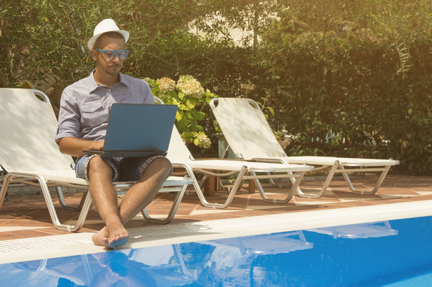 Guy working on laptop next to the swimming pool  - Photo, Image