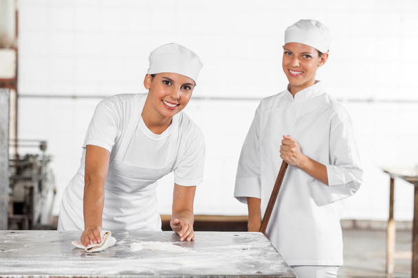 Smiling Female Bakers In Uniform Cleaning Bakery - Φωτογραφία, εικόνα