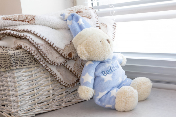 grey basket with childrens toys, diapers, accessories on table on grey wooden background. Mother care. childrens room, the pile of blue clothes for newborn boy - Photo, image