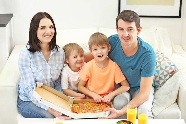 Happy family eating pizza on sofa all together - Fotoğraf, Görsel