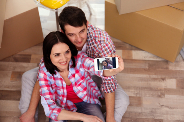 Young couple taking picture on the floor of their new house. Close up. - Fotó, kép
