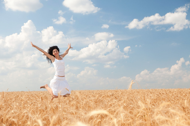 Happy woman jumping in golden wheat - Photo, Image