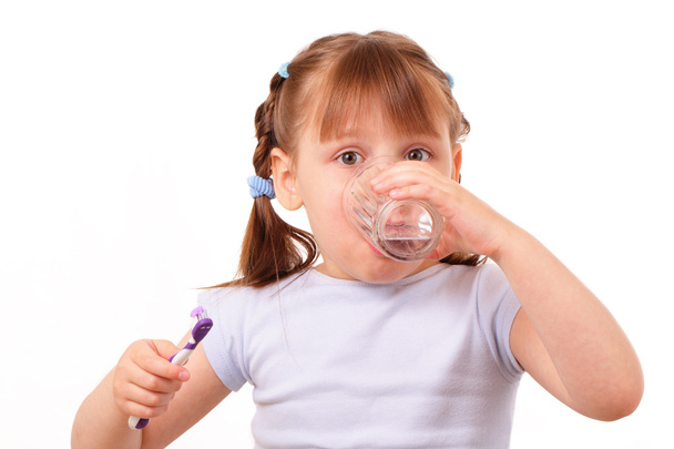 Little girl with a tooth brush drinks water from the glass - Photo, Image