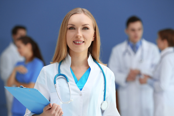 Женщина-врач со стетоскопом и коллеги в больнице
 - Фото, изображение