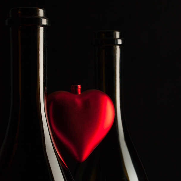 Silhouettes of elegant wine bottles with red heart  - Foto, afbeelding